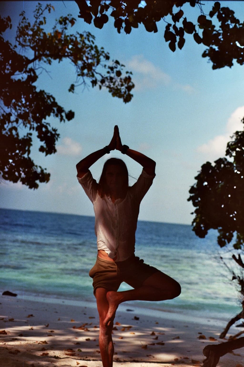 Silhouette practicing tree pose by the sea